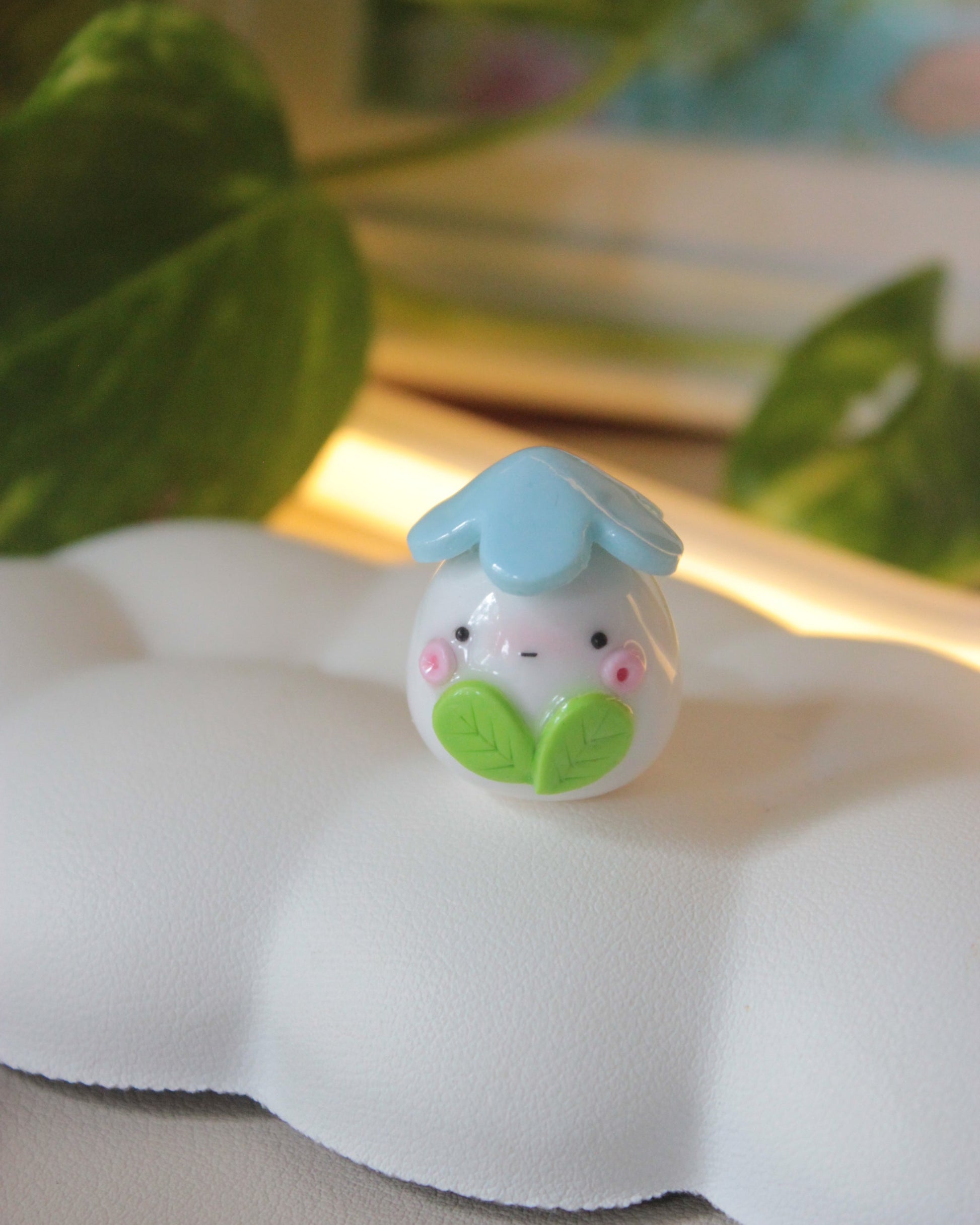 Small decorative item with a blue top and green leaves on a white surface.